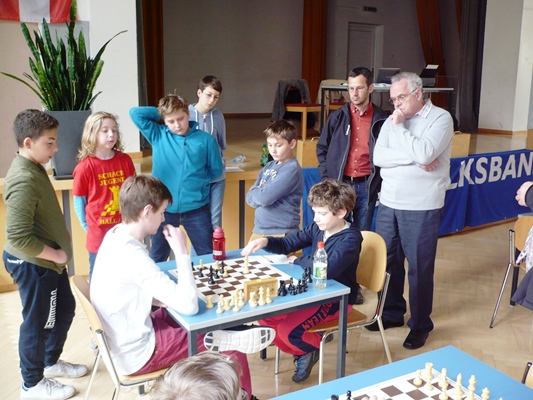 Laurin WISCHOUNIG und Quentin HALLER im Endspiel mit einem Extraläufer für Laurin. Da es die letzte Partie der Runde ist, gibt es einige Zuschauer: unter anderen Maximilian VINATZER (mitte), Quentins Vater und der Schiedsrichter Josef KREUTZ (rechts)